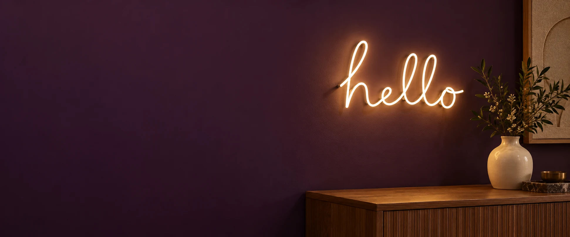 Warm-white hello neon sign on a plum wall